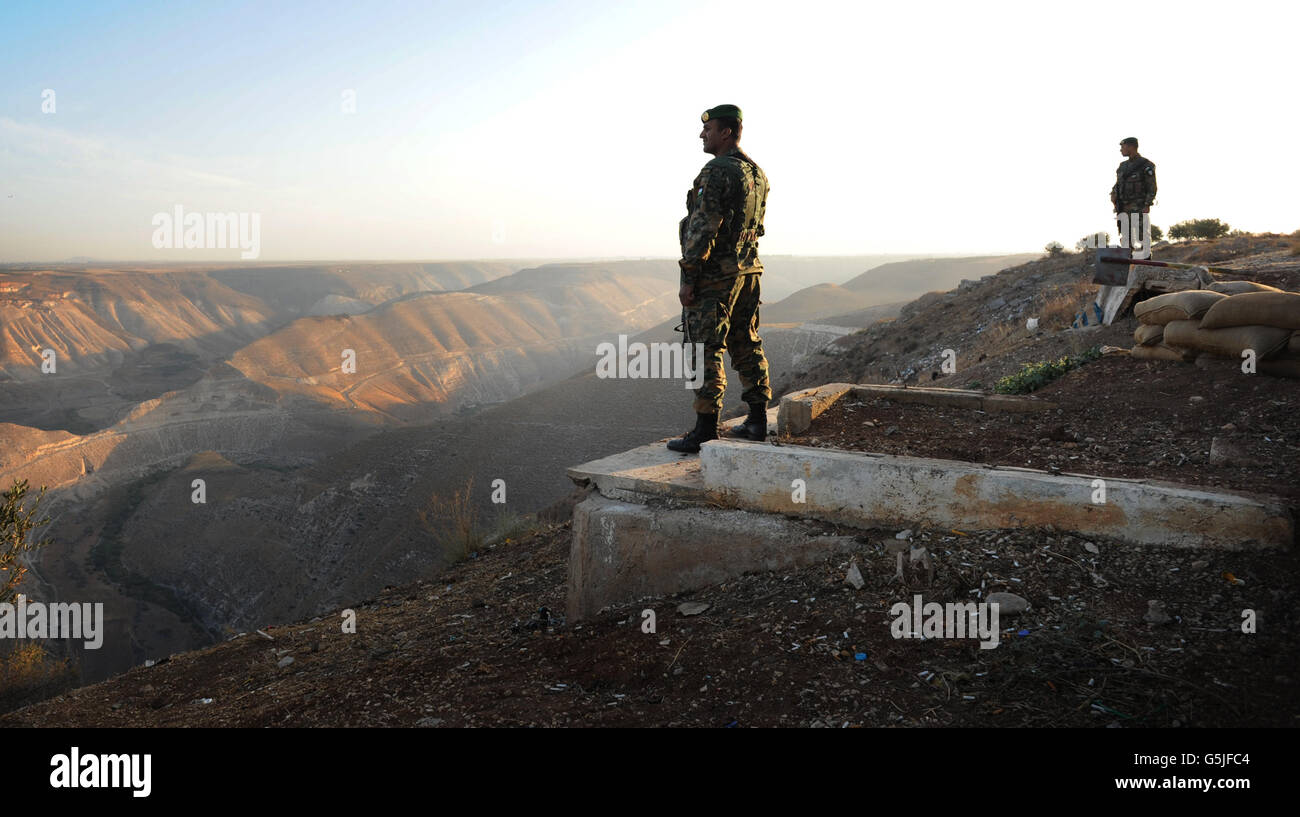 Jordanian border guards look out over Syria from Jordan near the site of the Al Wahdah Dam which is used by many Syrian refugees to escape the Assad regime. Stock Photo