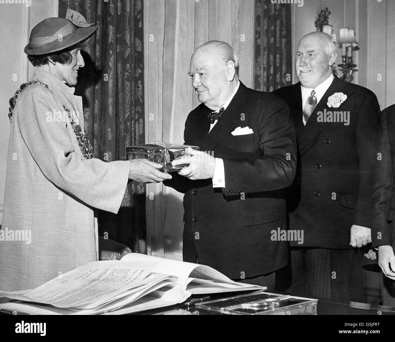 The Mayor of Poole (Dorset), Alderman Miss Margaret Mary Lllewellin hands Prime Minister Sir Winston Churchill a casket containing the certificate of his admission as a Freeman of the Borough of Poole. The ceremony was performed in the drawing room of 10 Downing Street, London. Stock Photo