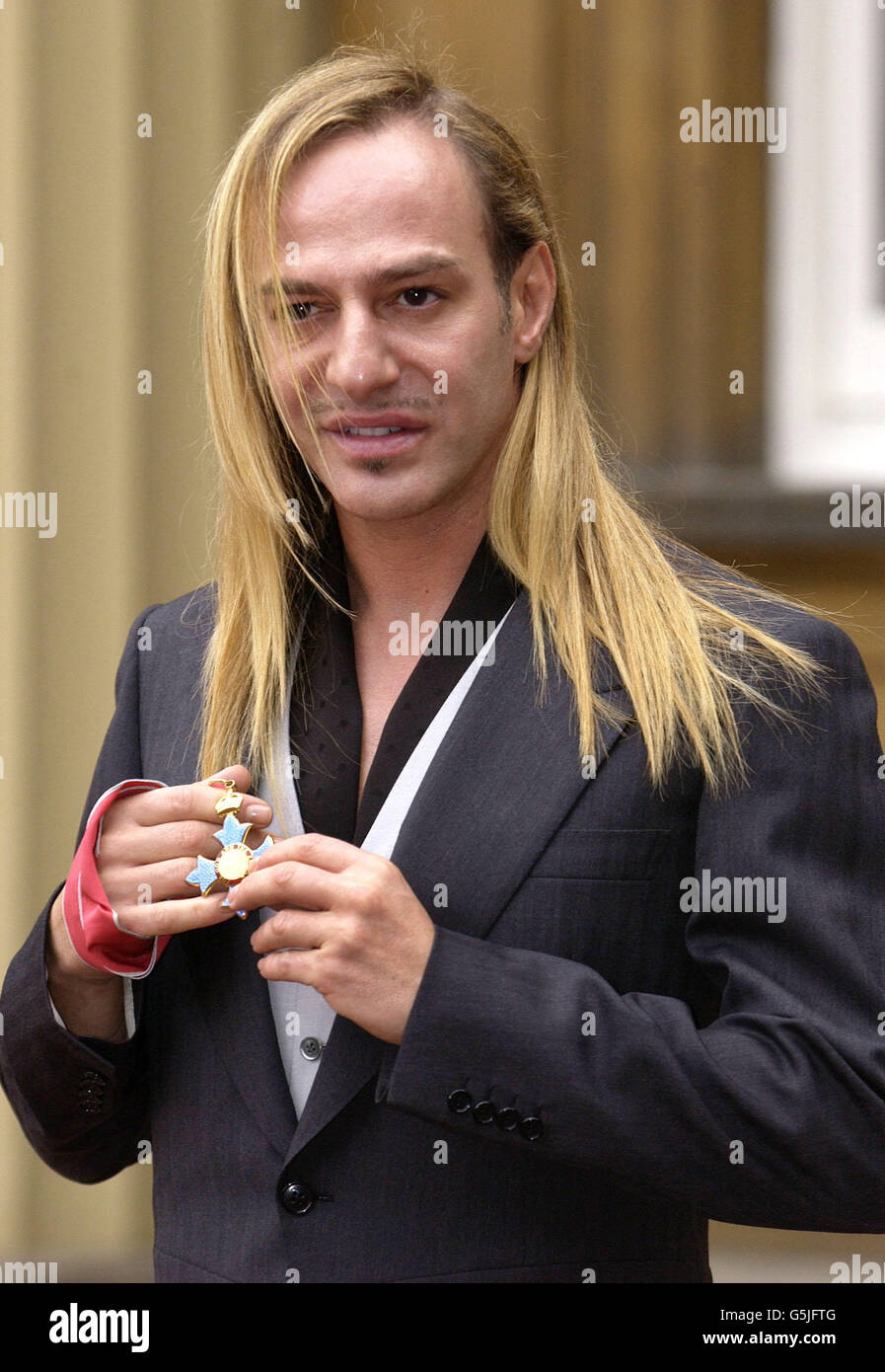 British fashion designer for Dior, John Galliano poses for photographs  after receiving an CBE from Queen Elizabeth II at Buckingham Palace,  London. He said it was one of the greatest honours he'd