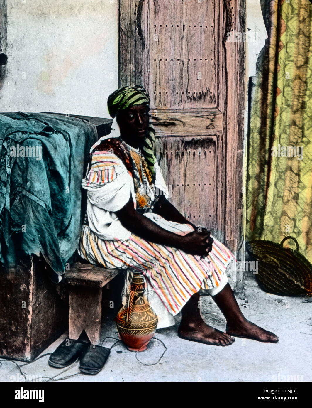 Eine farbige Frau sitzt vor einem Hauseingang in Algier, der Hauptstadt von Algerien, ca. 1920er Jahre. A black woman sitting in front of the entrance to a house at Algiers, capital of Algeria, ca. 1920s. Stock Photo