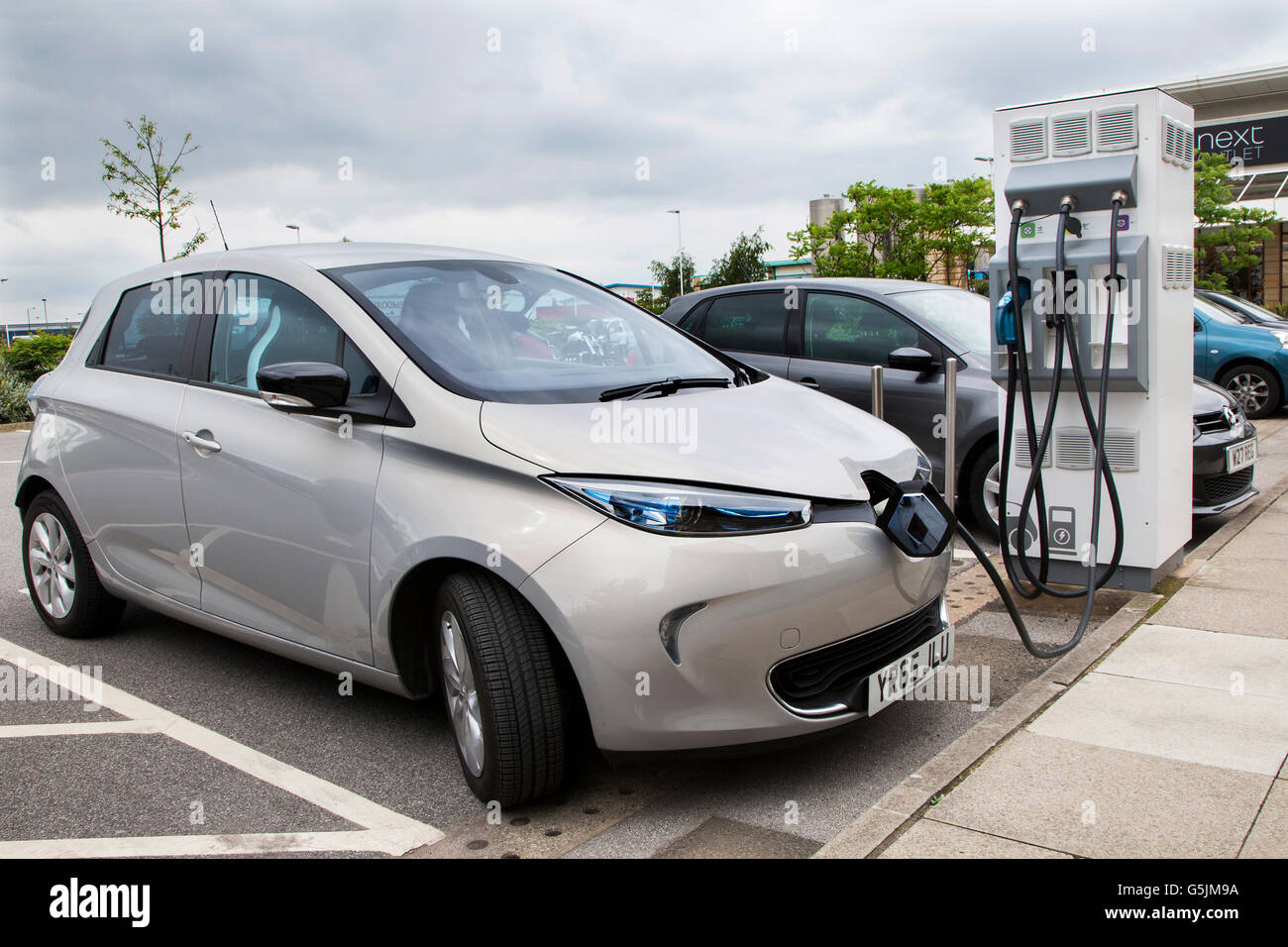 Electric Renault car charging at a recharging point in the car park of a retail shoppping outlet in Doncaster South Yorkshire Stock Photo