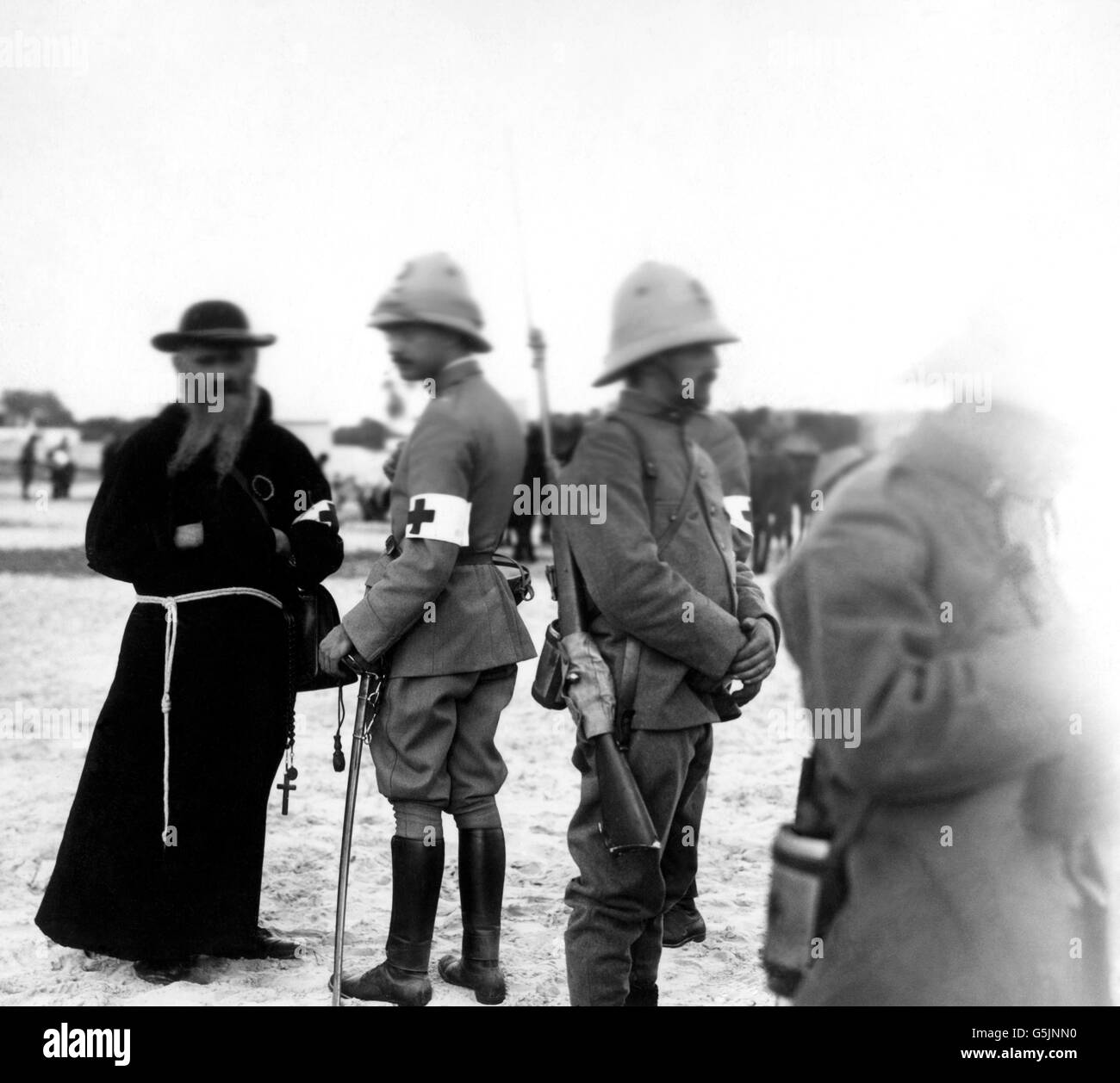 A Red Cross priest and Italian Army soldiers armed with swords and rifles. Stock Photo