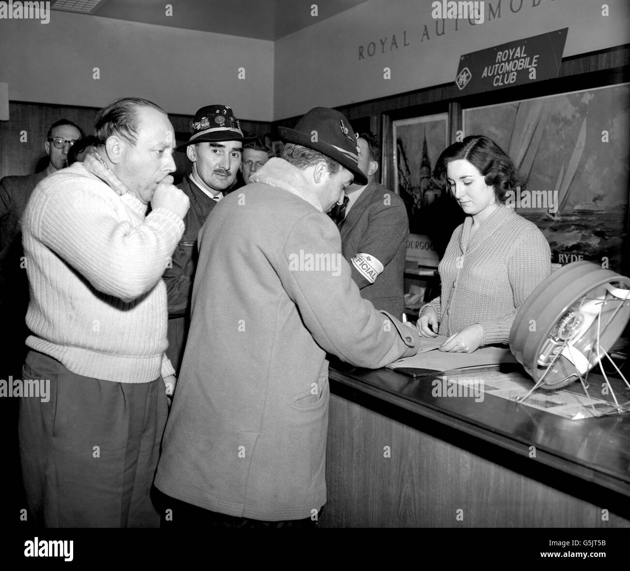 Eric Haddon of Buckinghamshire signs in at the ferry terminal in Dover, before heading to France to take part in the Monte Carlo Rally. On the left is Mr C Vivian, while behind the desk is Valerie Triggs, a Royal Automobile Club port official. Stock Photo