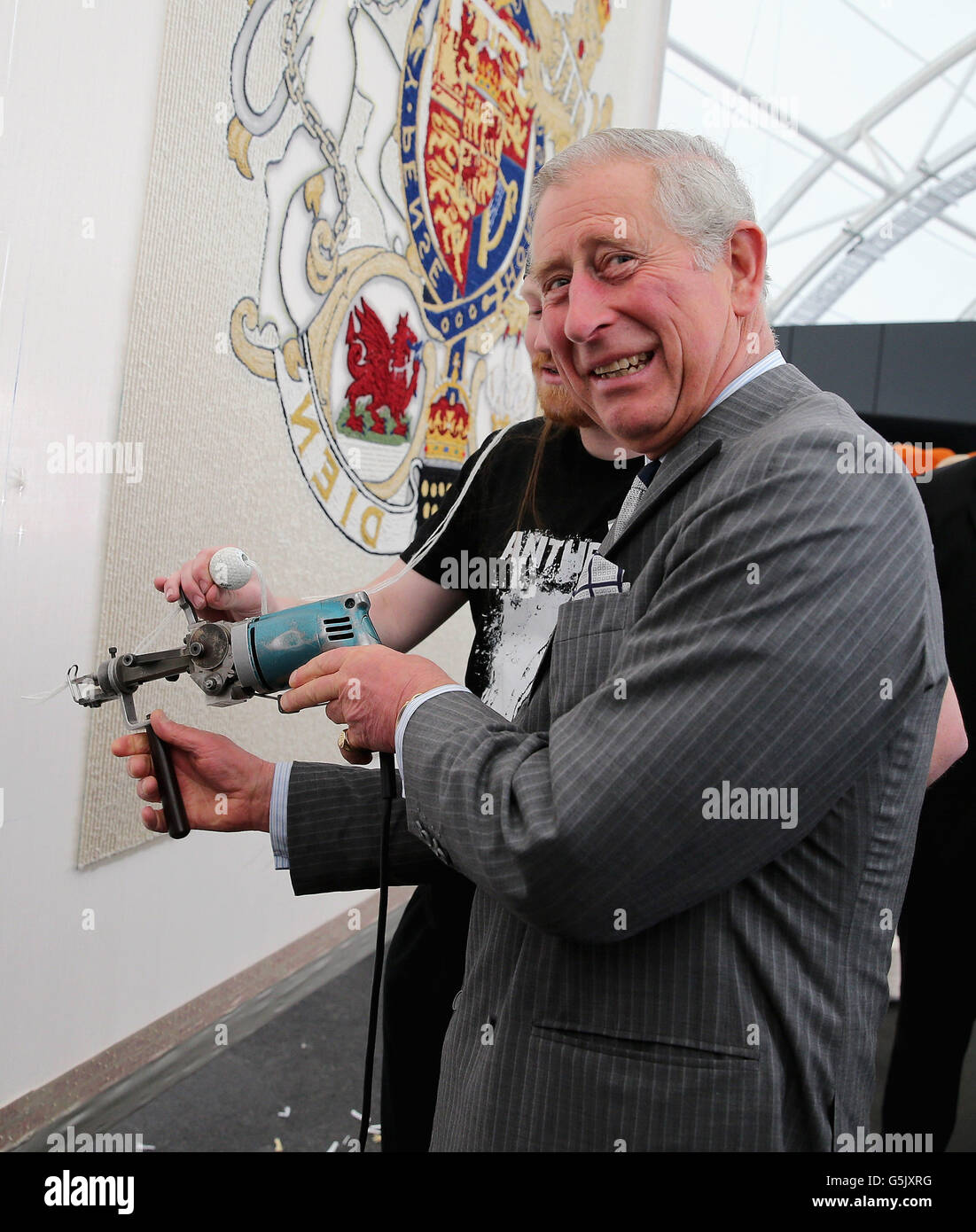 The Prince of Wales uses a 'tufting gun' to work on a wool carpet featuring the royal crest at a New Zealand Sheer Brilliance event in the Cloud in Auckland, New Zealand. Stock Photo