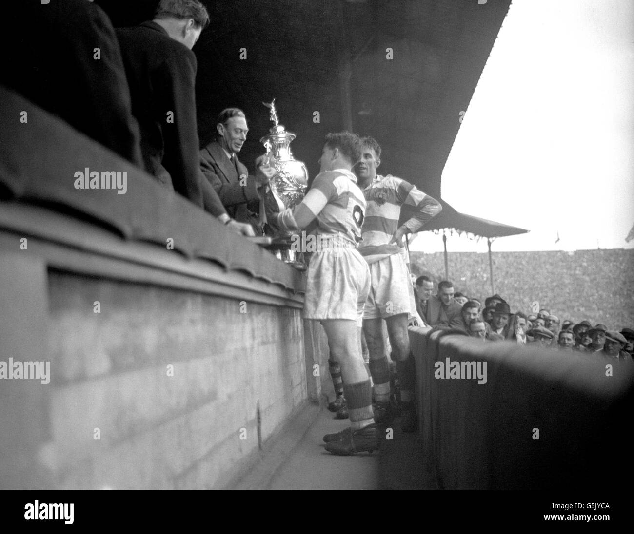 King George VI presents the Challenge Cup to Joe Egan, captain of Wigan, after Wigan had beaten Bradford Northern 8-3 in the cup final held at Wembley. Stock Photo