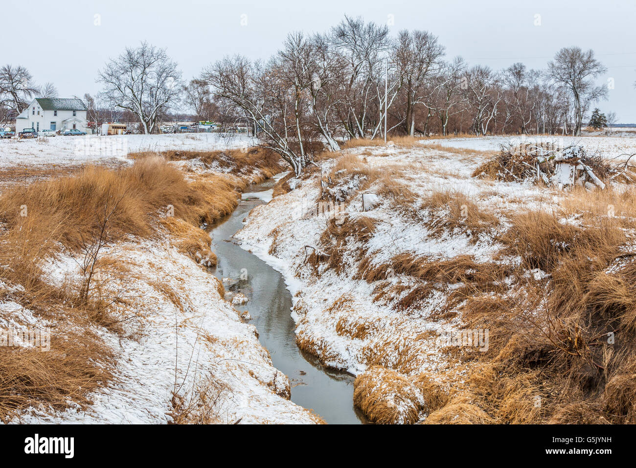 Creek running through snow dusted farm land in rural north eastern