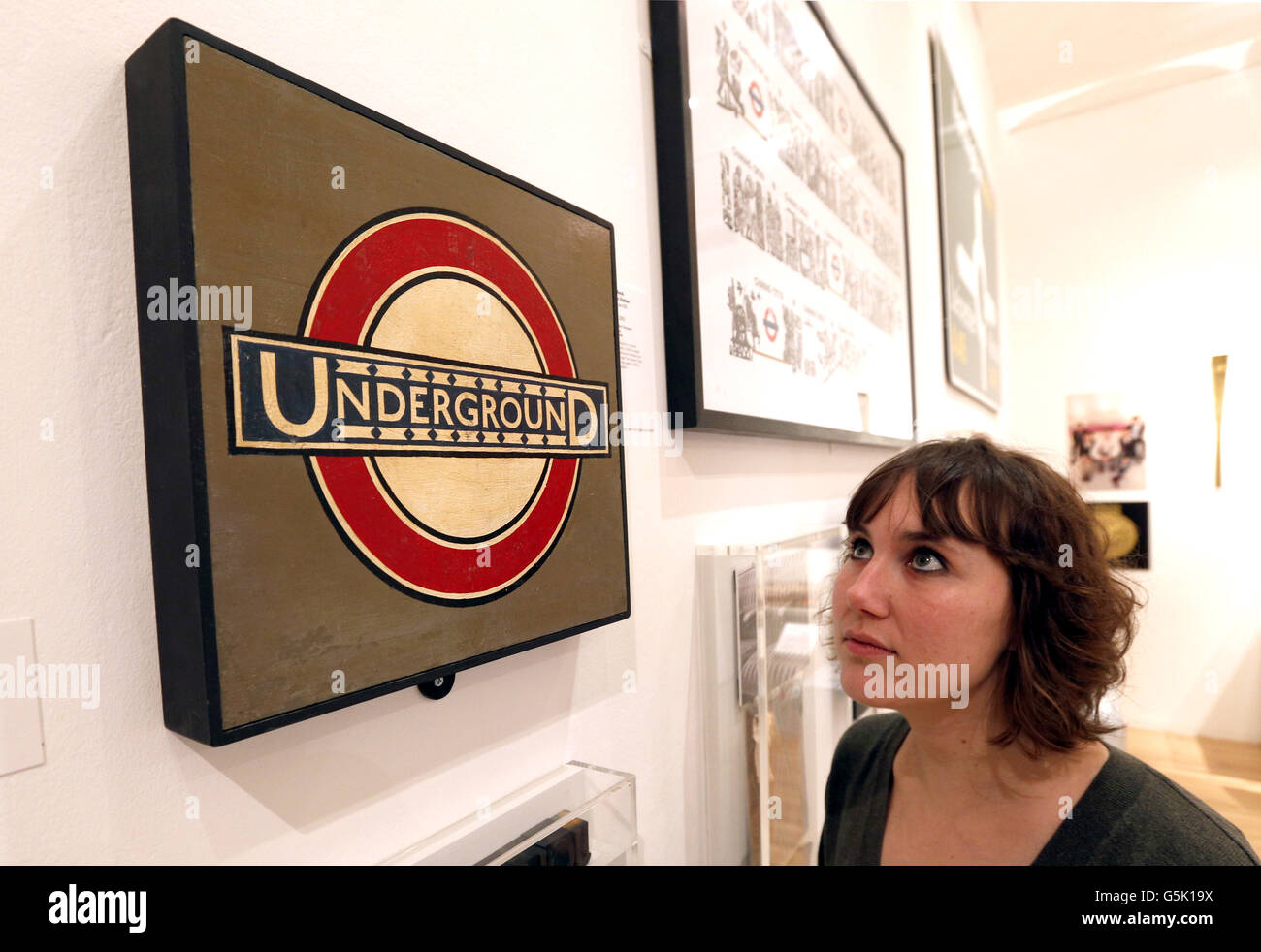 A member of staff looks at Edward Johnston's 'Westminster Underground Roundel' during a preview of the Royal College of Art's 'The Perfect Place to Grow: 175 Years of the Royal College of Art' exhibition at the Royal College of Art, London. Stock Photo