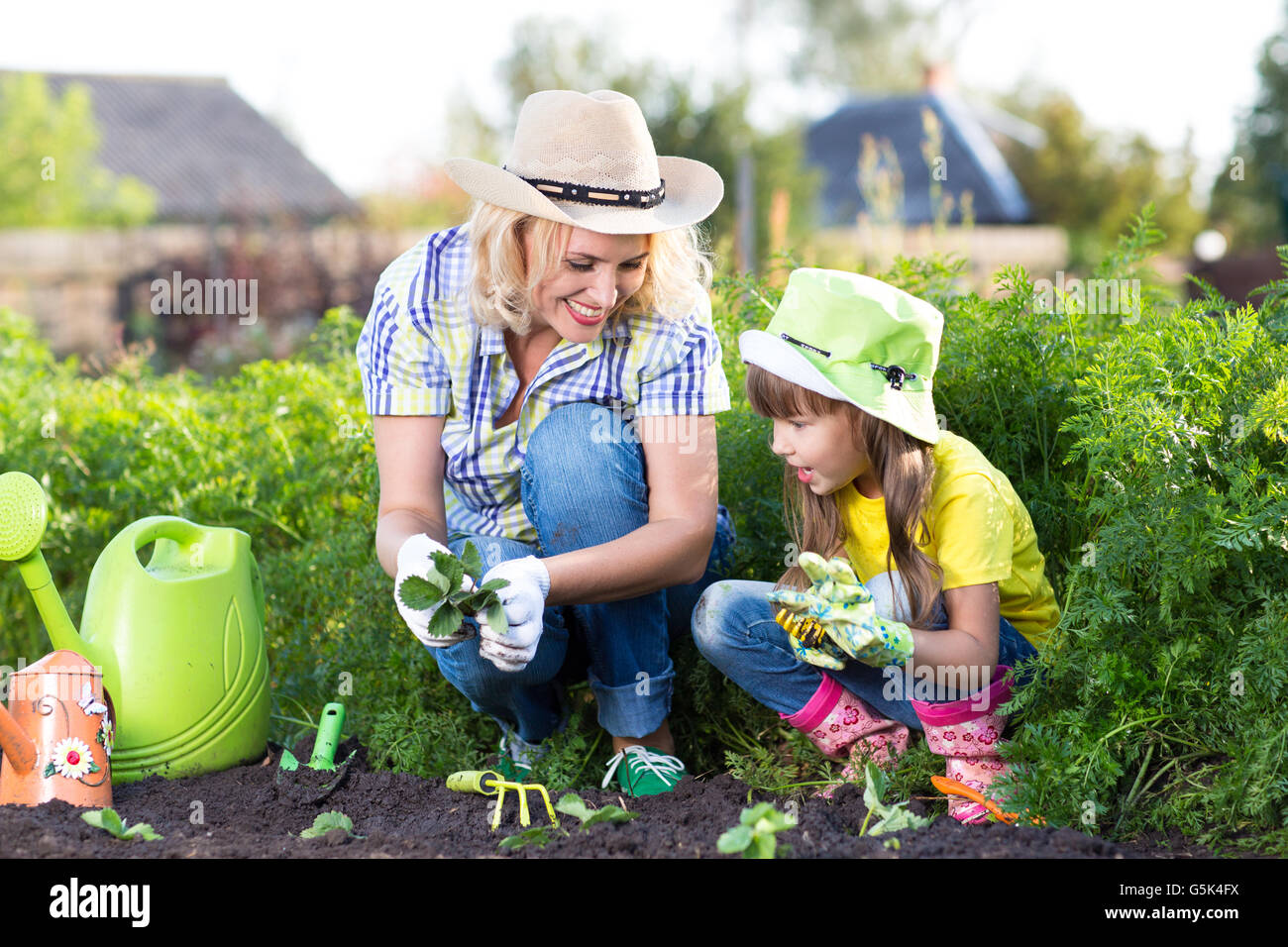 Mother and daughter child planting strawberry seedlings in summer Stock Photo