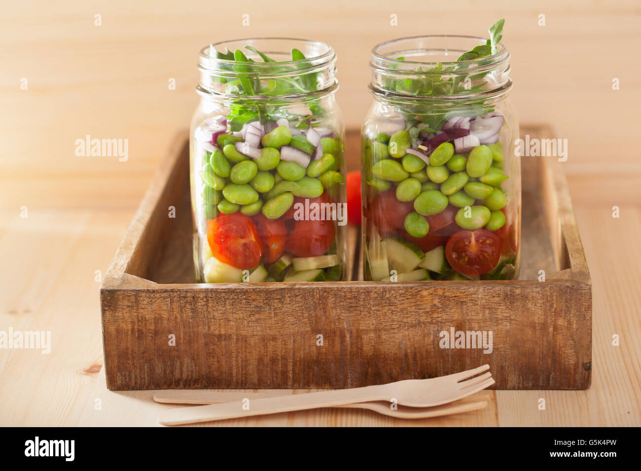healthy vegetable salad in mason jar tomato, cucumber, soybean, onion