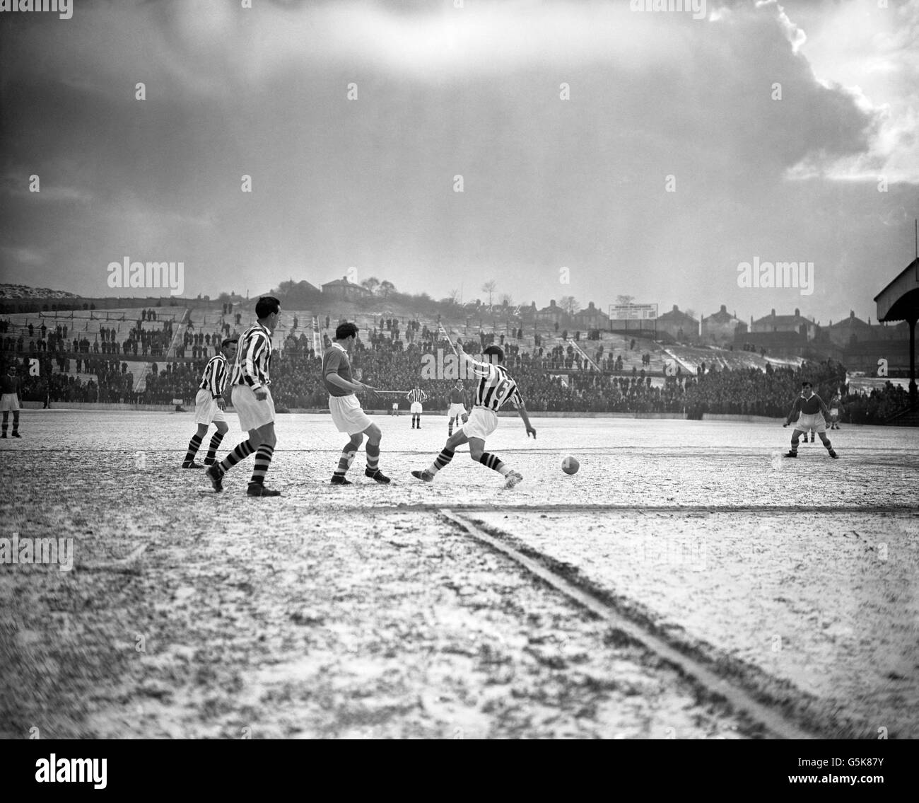 Gerry Summers (no.6) runs across the snow-covered pitch during West Bromwich Albion's First Division match against Charlton Athletic at The Valley, London. On the left is Ronnie Allen (no.10). Stock Photo