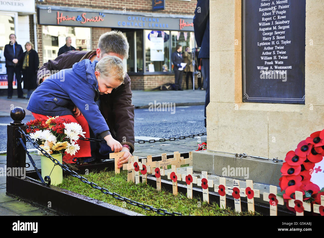 People young and old place crosses of remembrance on the war memorial on the High Street of Royal Wootton Bassett, where a service of remembrance and two minutes silence is being observed in the Wiltshire town that is now synonoymous with the repatriation of fallen service personnel. Stock Photo
