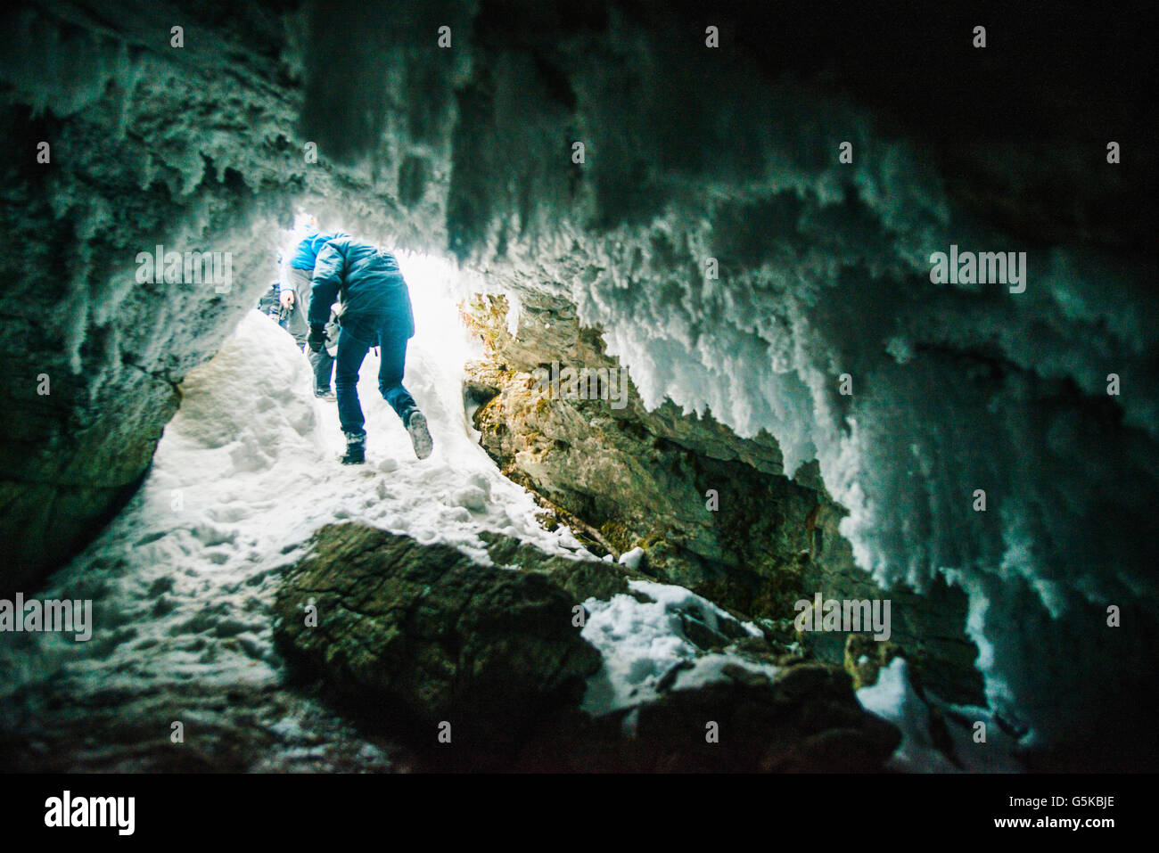 Caucasian hiker walking in icy cave Stock Photo