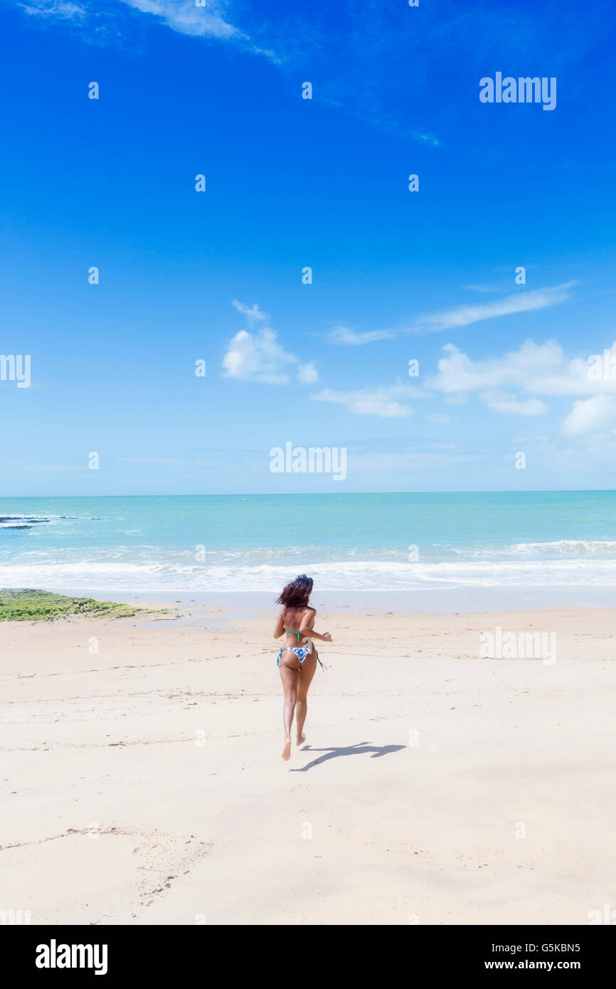 Hispanic woman running on beach Stock Photo