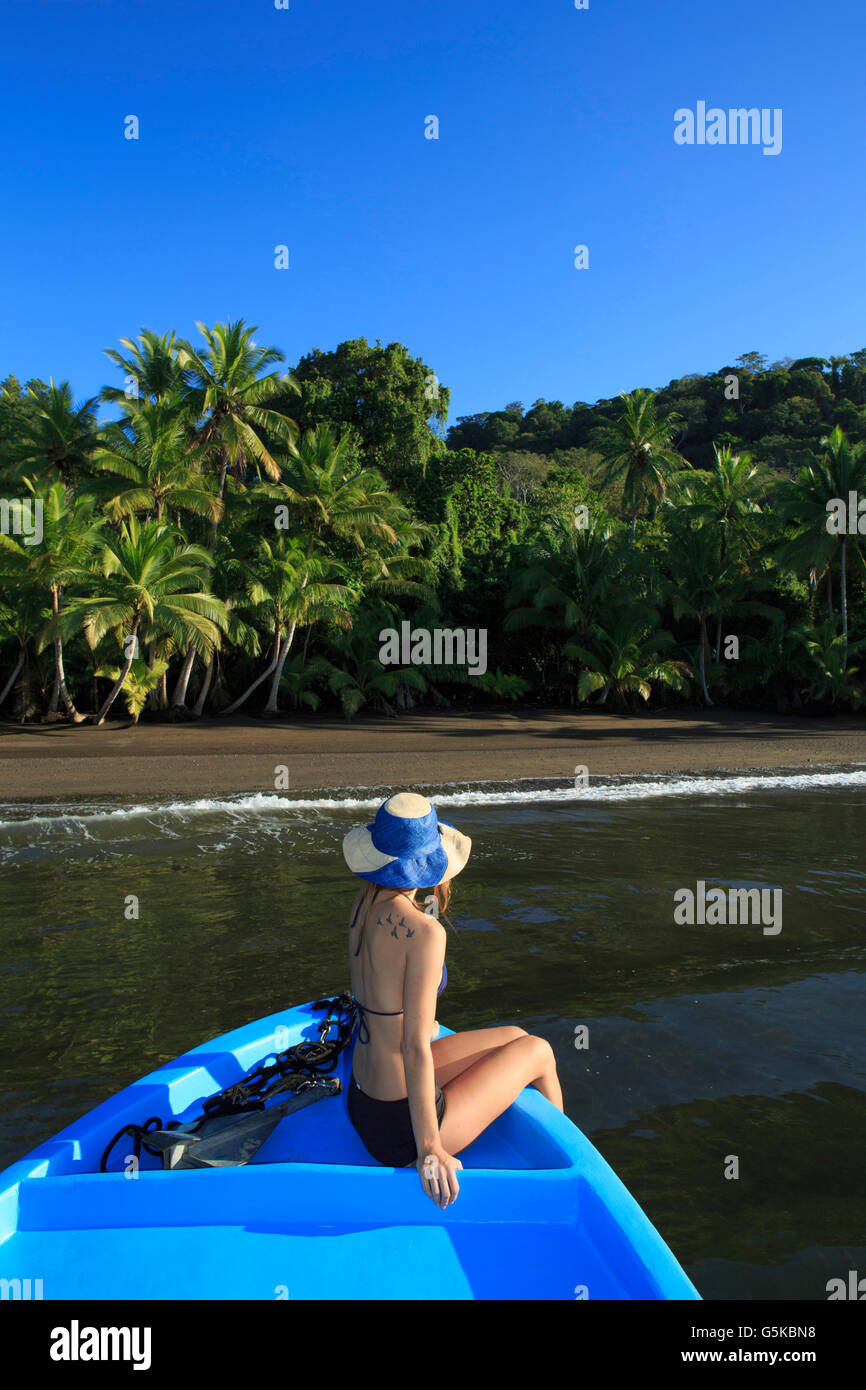 Hispanic woman sitting in boat near beach Stock Photo