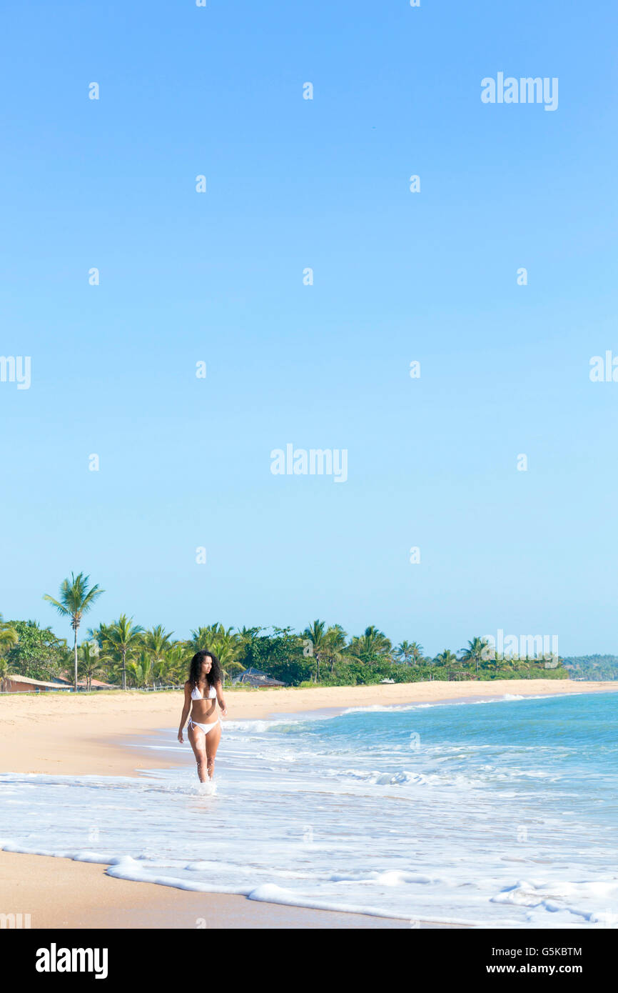 Mixed race woman walking on beach Stock Photo