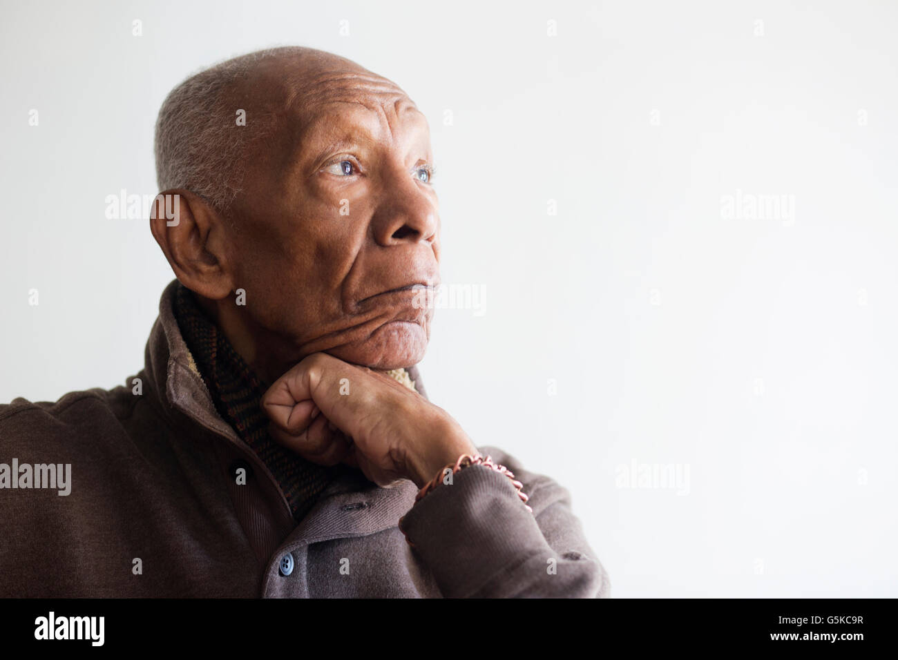 Older Black man resting chin in hand Stock Photo