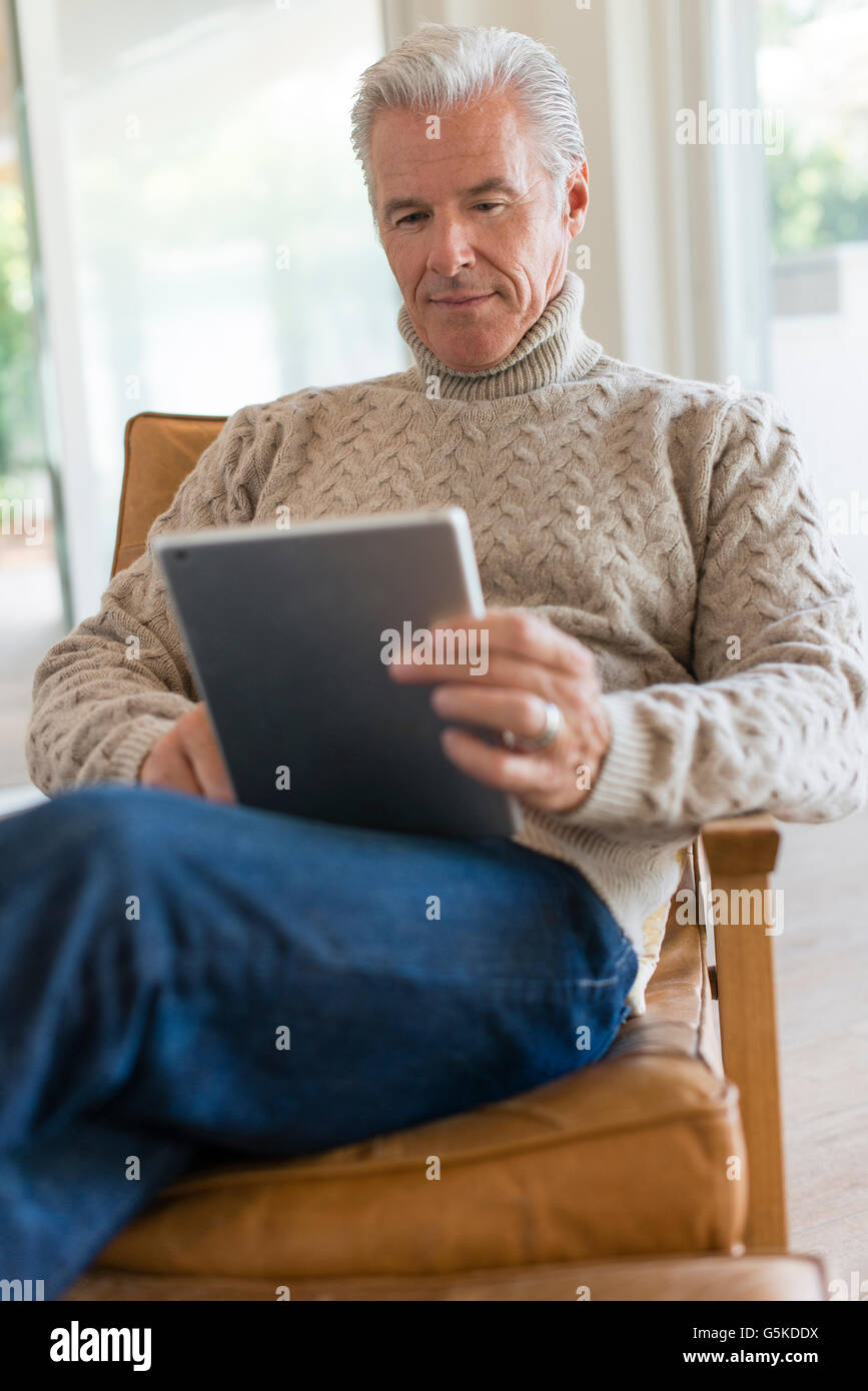 Caucasian man using digital tablet in armchair Stock Photo
