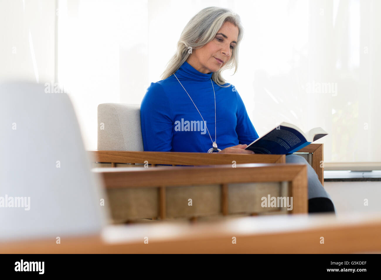 Caucasian woman reading book in armchair Stock Photo - Alamy