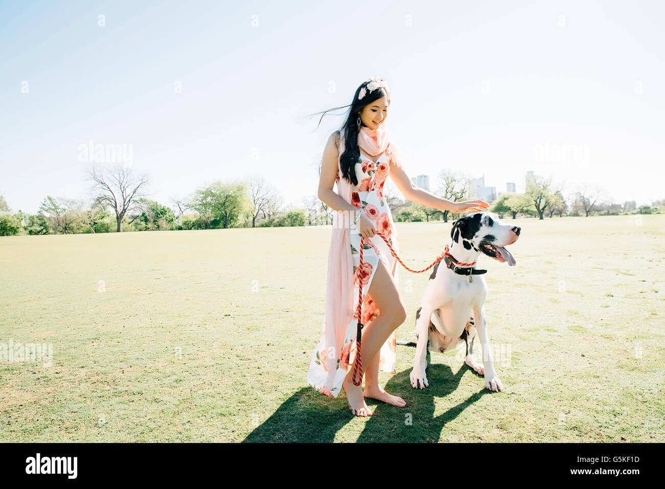 Chinese woman walking dog in field Stock Photo
