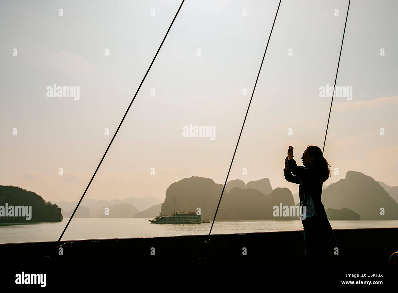 Caucasian woman photographing rock formations in Ha Long Bay, Vietnam Stock Photo