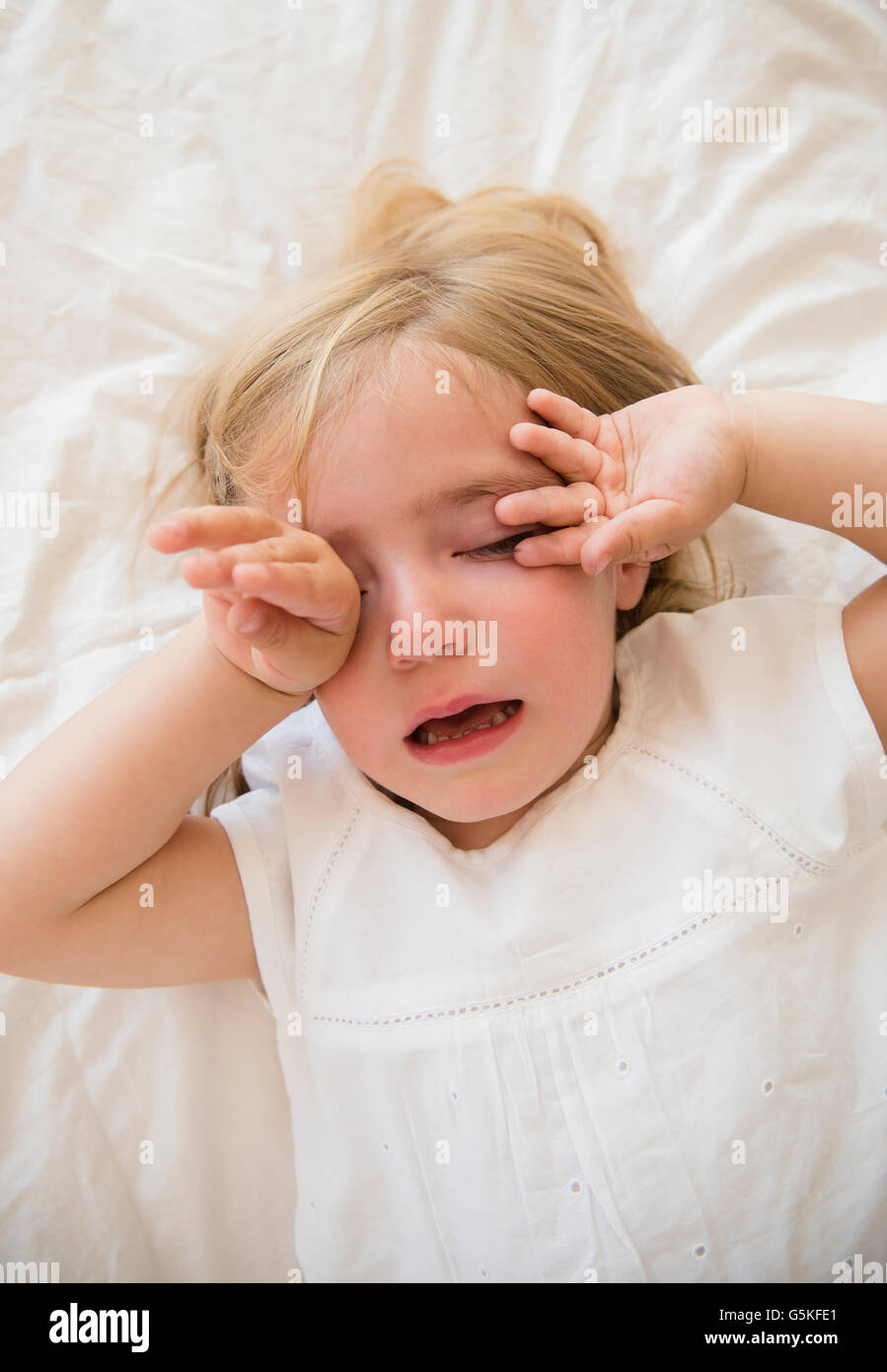 Caucasian girl crying on bed Stock Photo