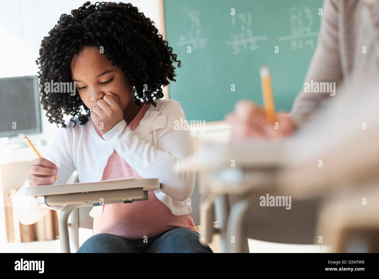 African American student writing in classroom Stock Photo