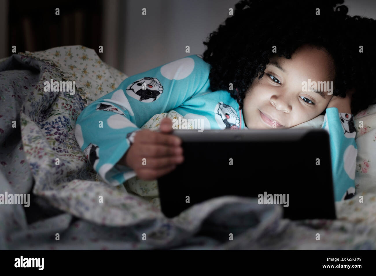 African American girl using digital tablet in bed Stock Photo