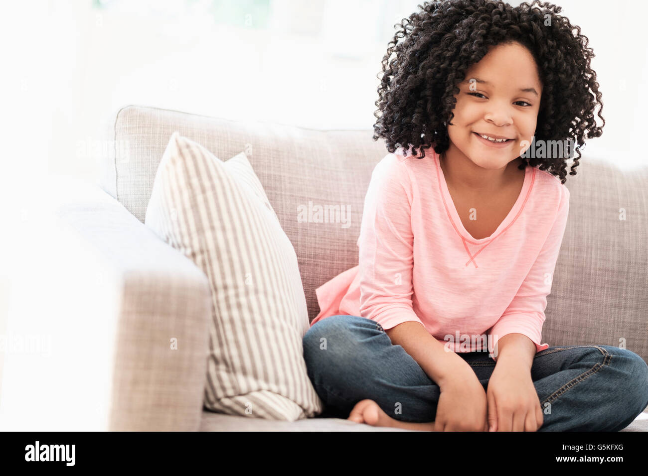 African American girl smiling on sofa Stock Photo - Alamy