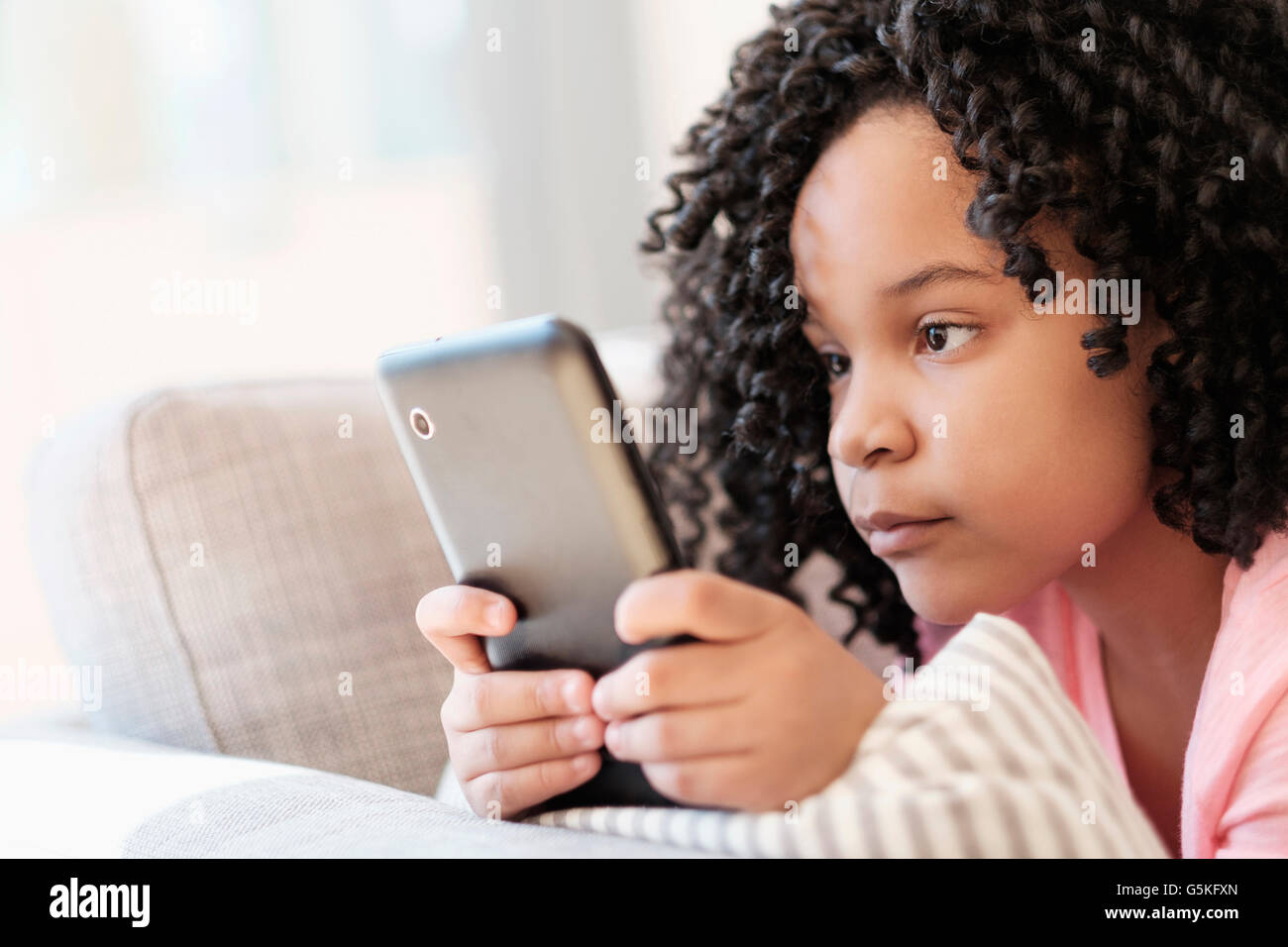 African American girl using cell phone on sofa Stock Photo