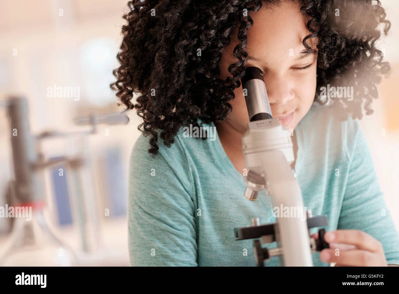 African American girl using microscope in science classroom Stock Photo