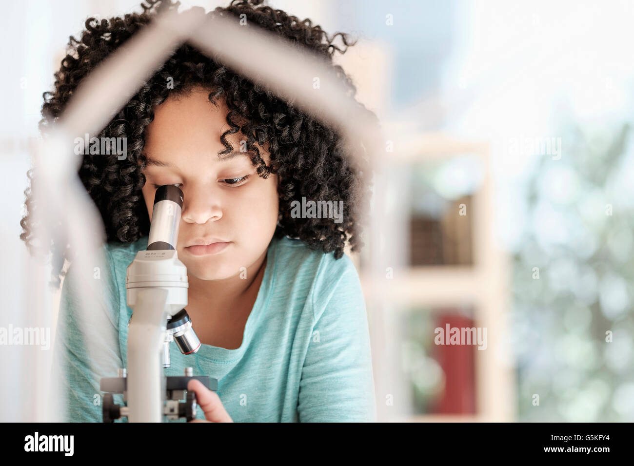 African American girl using microscope in science classroom Stock Photo