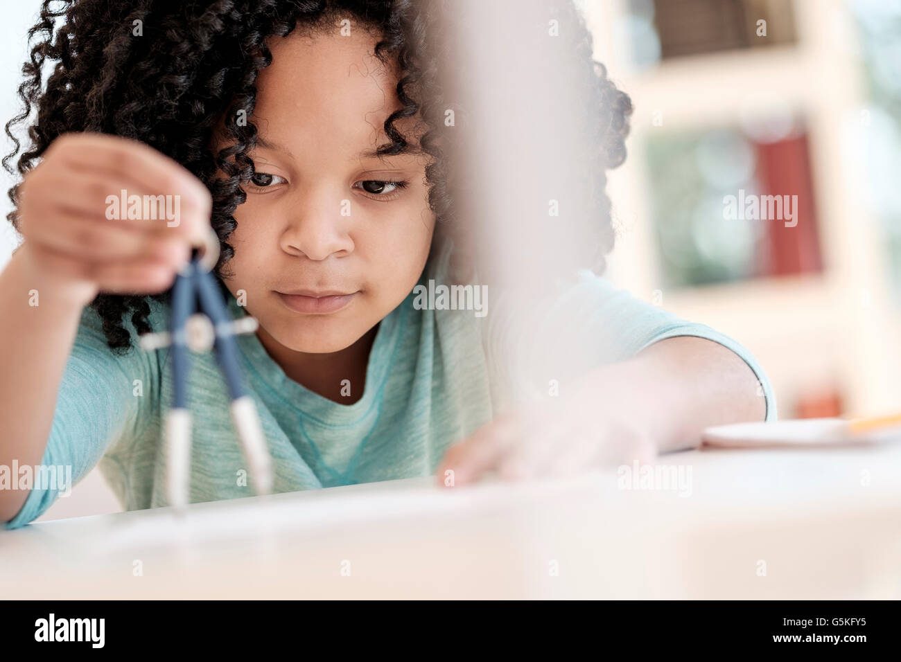African American girl using compass in science classroom Stock Photo