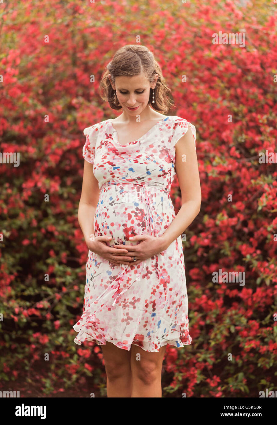 Pregnant Caucasian woman holding her belly outdoors Stock Photo - Alamy