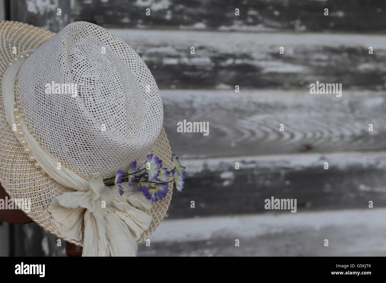 antique womans white hat with flowers against weathered gray barn siding lumber Stock Photo