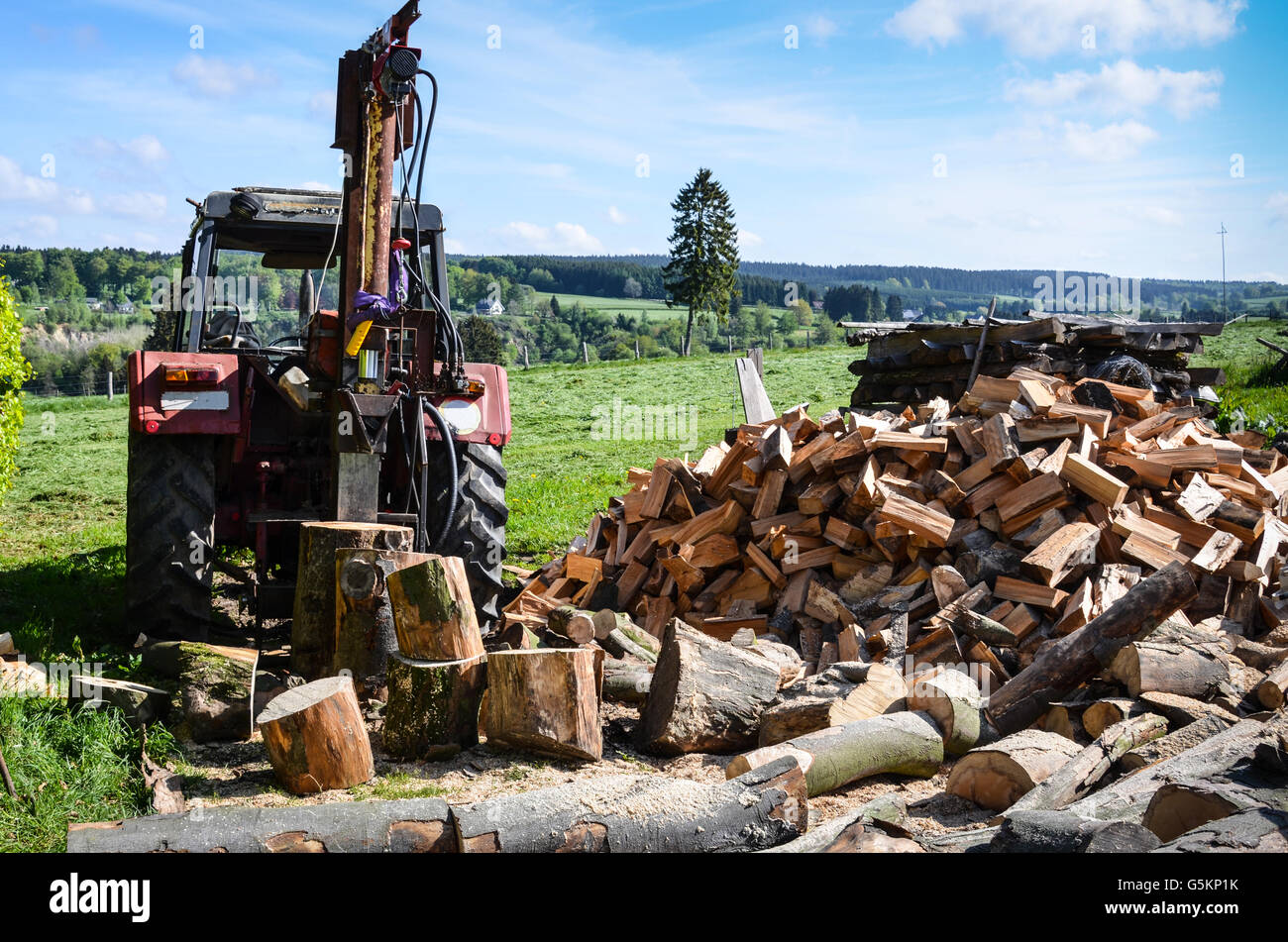 Old tractor with hydraulic powered log splitter and pile of firewood Stock Photo