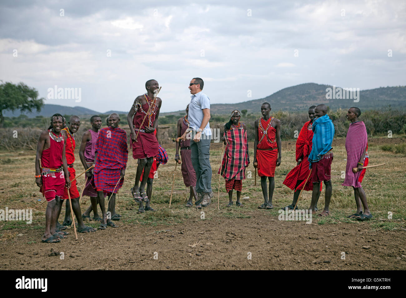 Group of Maasai warriors and one tourist doing a ceremonial dance in a Maasai village, Kenya, Africa. Stock Photo