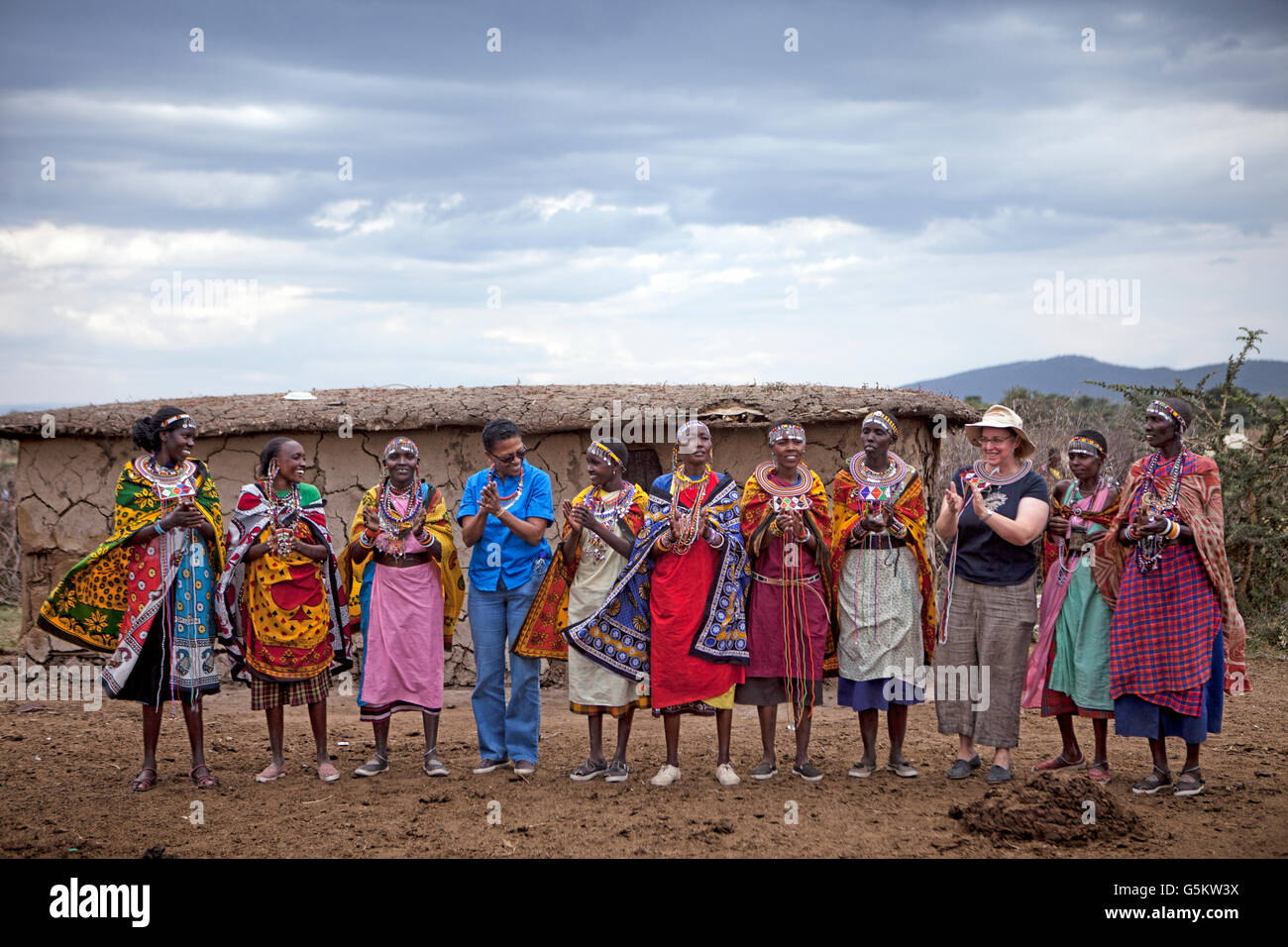 Group of Masai women and two tourists doing a ceremonial dance in a Masai village, Kenya, Africa. Stock Photo