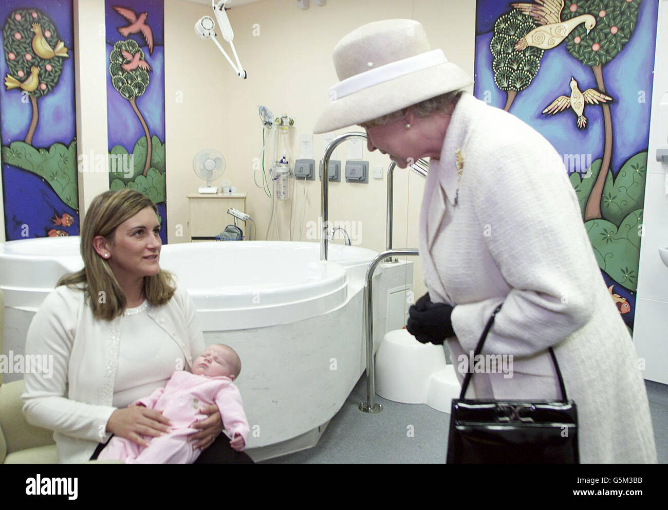 Britain's Queen Elizabeth II talks with Selina Mayne, with one-month-old daughter Ella, who told her what it was like to experience a water birth, at the birthing pool of the newly reconstructed Queen Elizabeth Hospital in Woolwich, south east London. *...The hospital project was completed with a Private Finance Initiative. Stock Photo