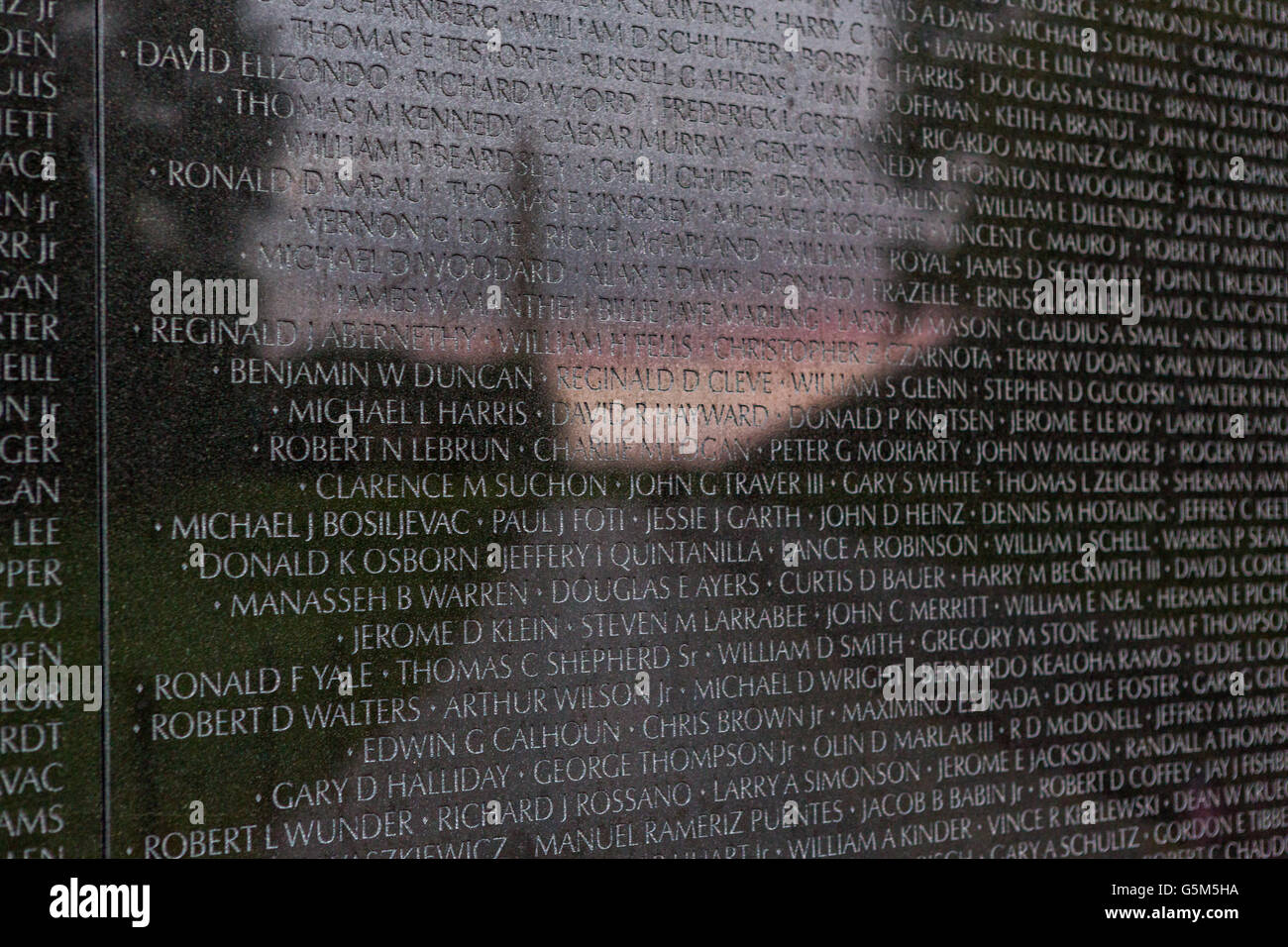Sunset and the Washington Monument is reflected on the names etched into the Vietnam Veterans Memorial Wall in Washington, DC. Stock Photo