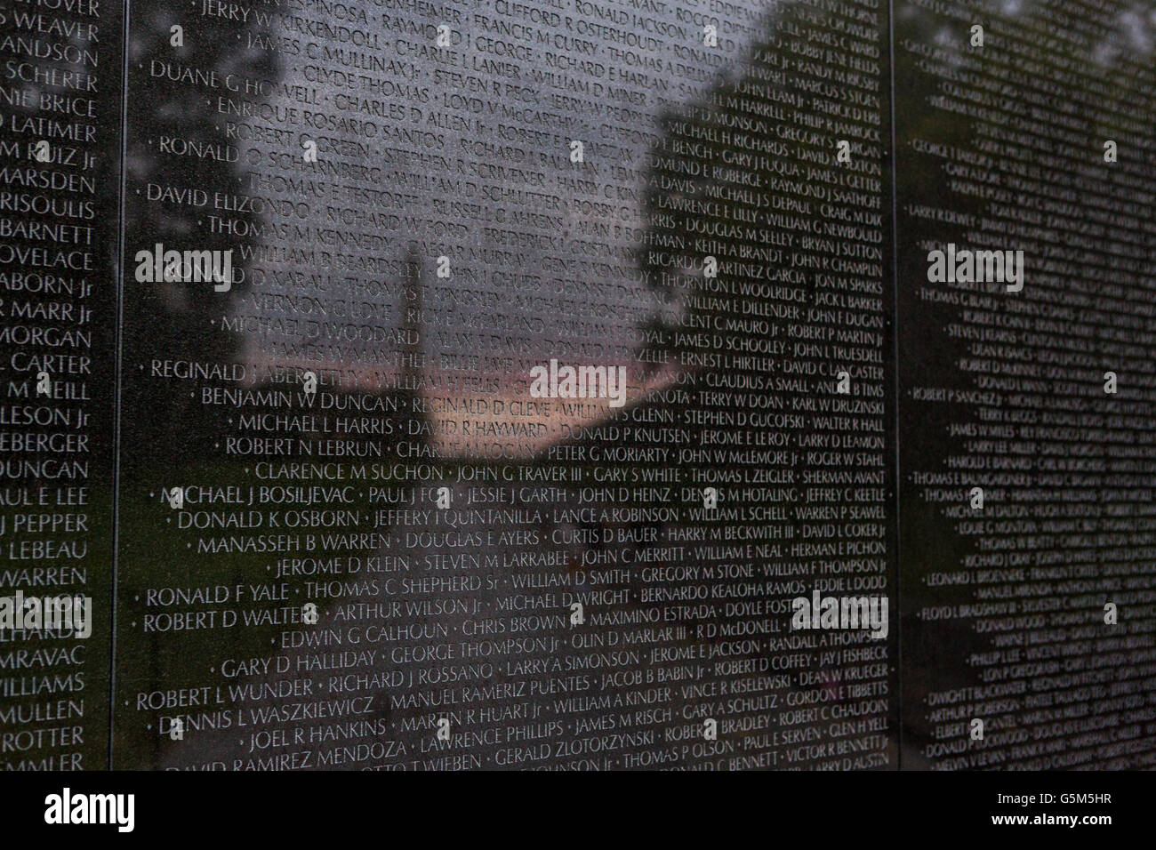 Sunset and the Washington Monument is reflected on the names etched into the Vietnam Veterans Memorial Wall in Washington, DC. Stock Photo