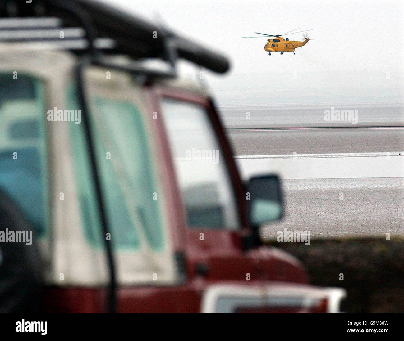 An air sea rescue helicopter searches for the missing boy close to the jeep where his father parked the vehicle (left) before they were trapped by rising tides near Ulverston. The body of the 51-year-old man, who has not been named, was found at Bardsea. *..., in an area of sandbanks and mud flats about two kilometres from the high water mark at Bardsea. The search for the pair started yesterday afternoon when the father made a frantic 999 call saying he and his son were lost on the beach in swirling fog and facing a fast-incoming tide. Stock Photo