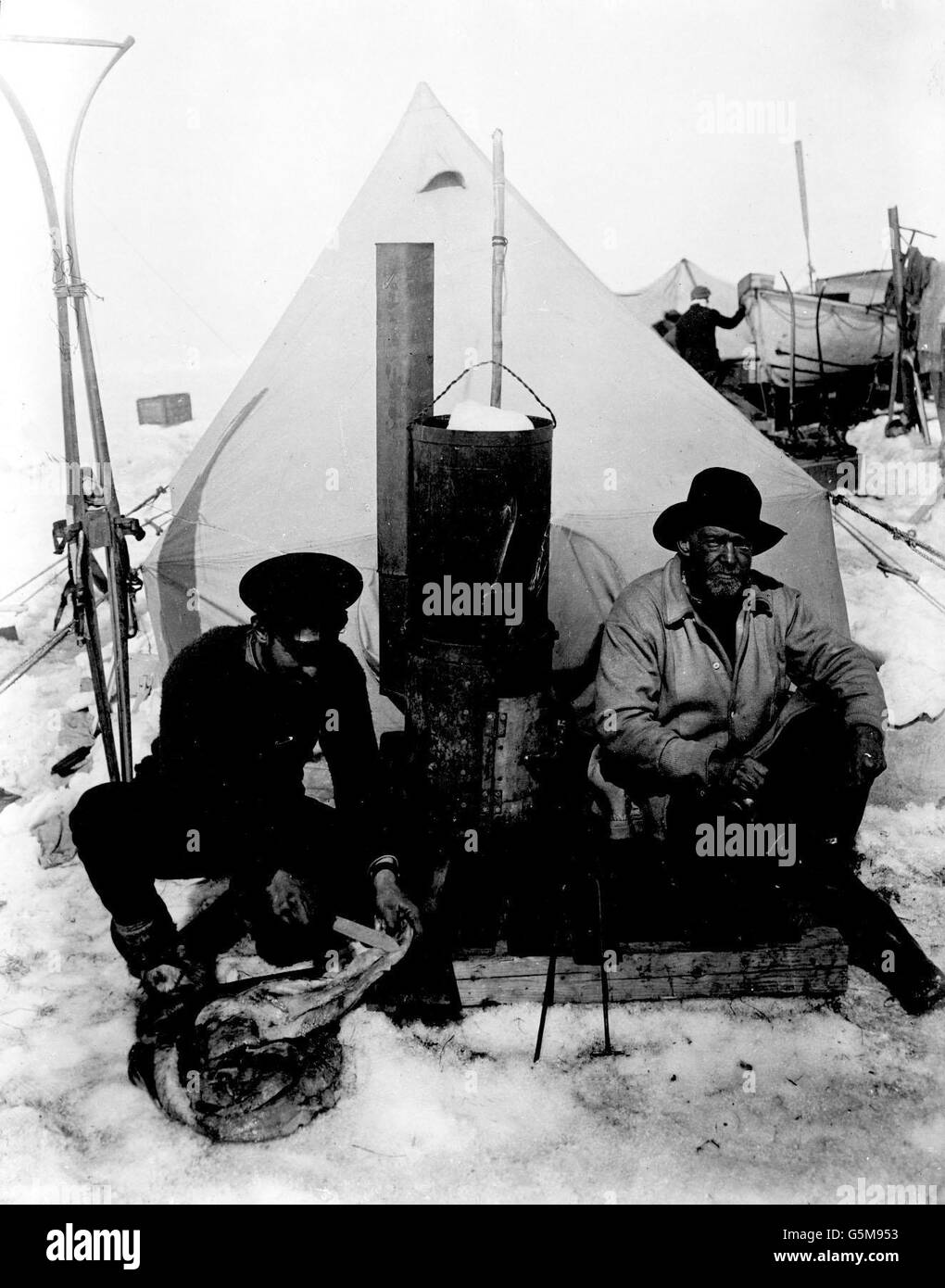 1916: Sir Ernest Shackleton (r) and Frank Hurley in front of their tent on the drifting ice floe called 'Patience Camp'. In the middle can be seen the stove on which all the cooking was done, the fuel being blubber and penguin skins. Mr Huley took all the photographs of the expedition. Stock Photo