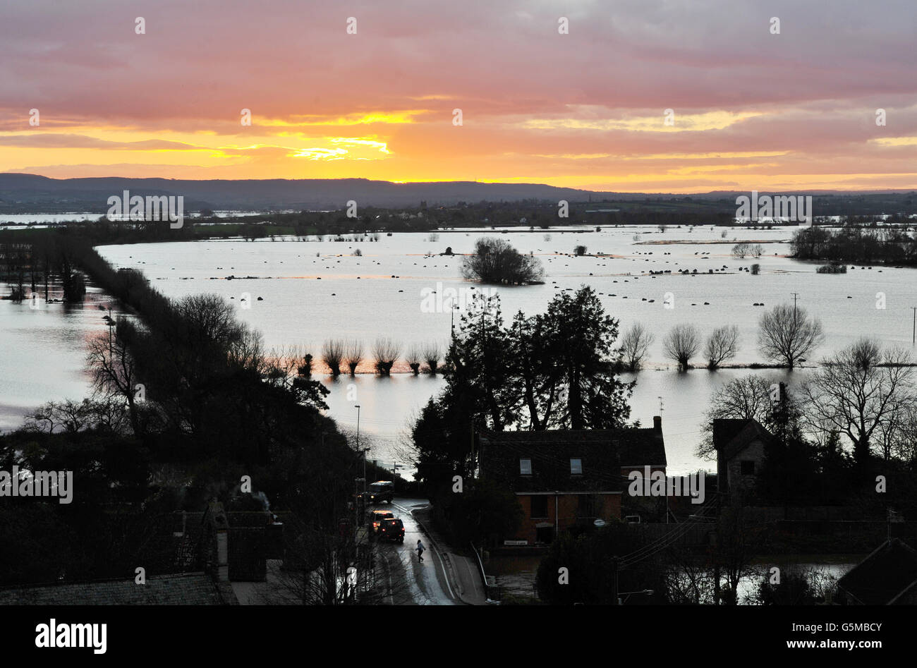The sun sets over floodwater in Somerset from Burrow Mump where the River Tone joins the River Parrett as water levels remain high despite a dry day. Stock Photo