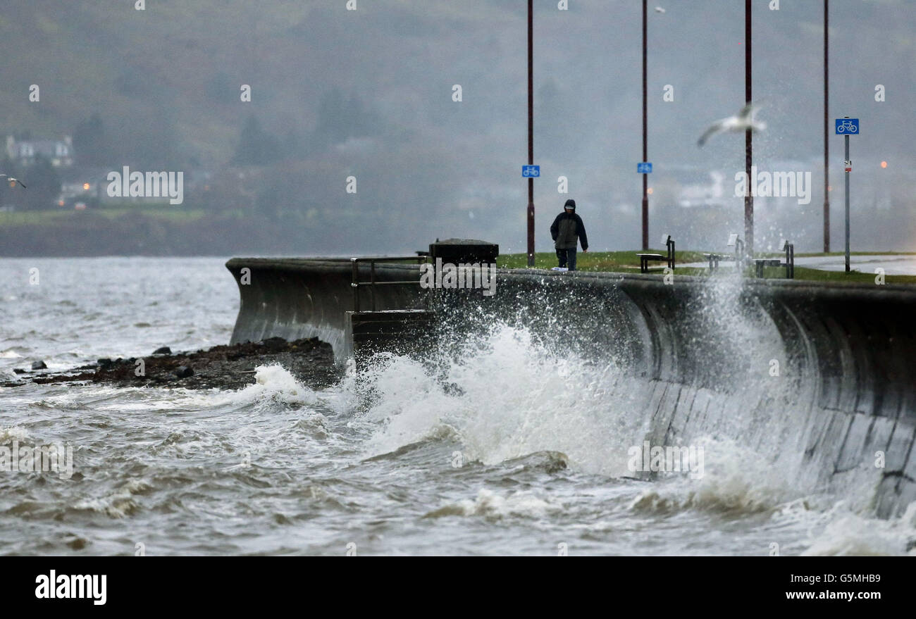 A man walks along the sea front in Helensburgh, Scotland, as the UK is braced for another day of deluges and flooding as heavy rain sweeps across the country. Stock Photo