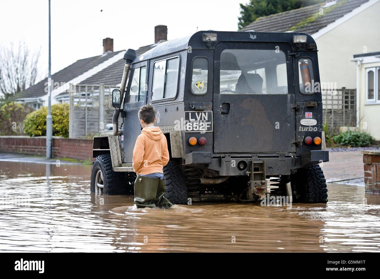 A boy inspects a 4x4 vehicle as it manages to keep above the water in the Somerset village of Ruishton, near Taunton, which has been flooded after the River Tone burst it's banks. Stock Photo