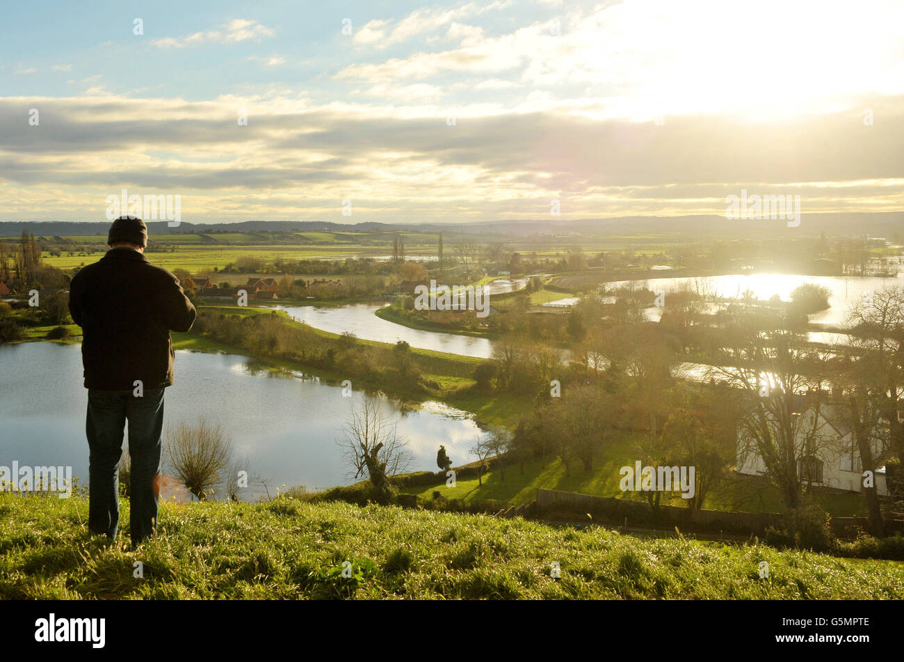 A man looks out over floodwater in Somerset from Burrow Mump where the River Tone joins the River Parrett as water levels remain high despite a dry day. Stock Photo
