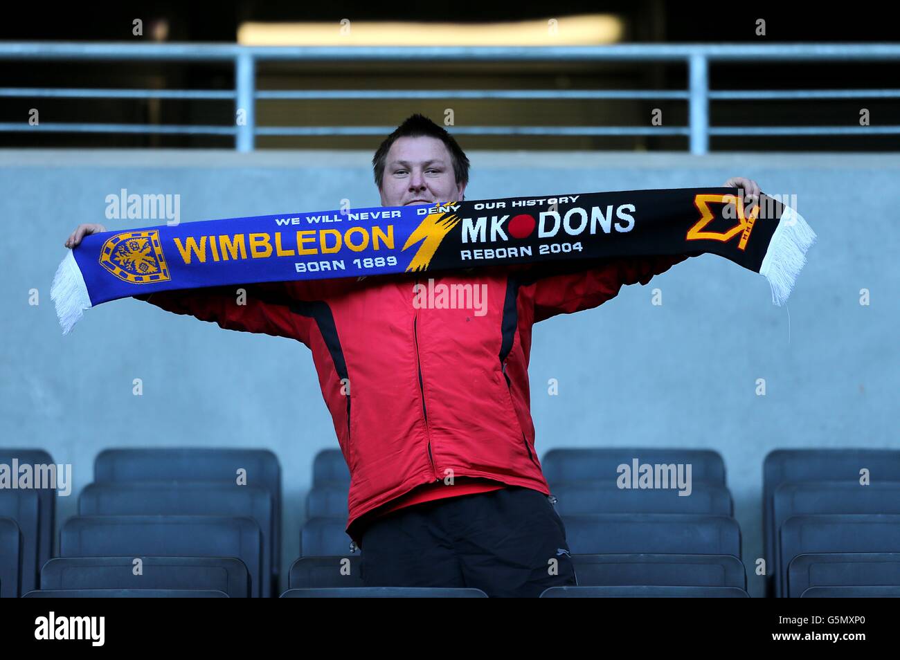 A Milton Keynes Dons fan holds up a Wimbledon & MK Dons scarf in the