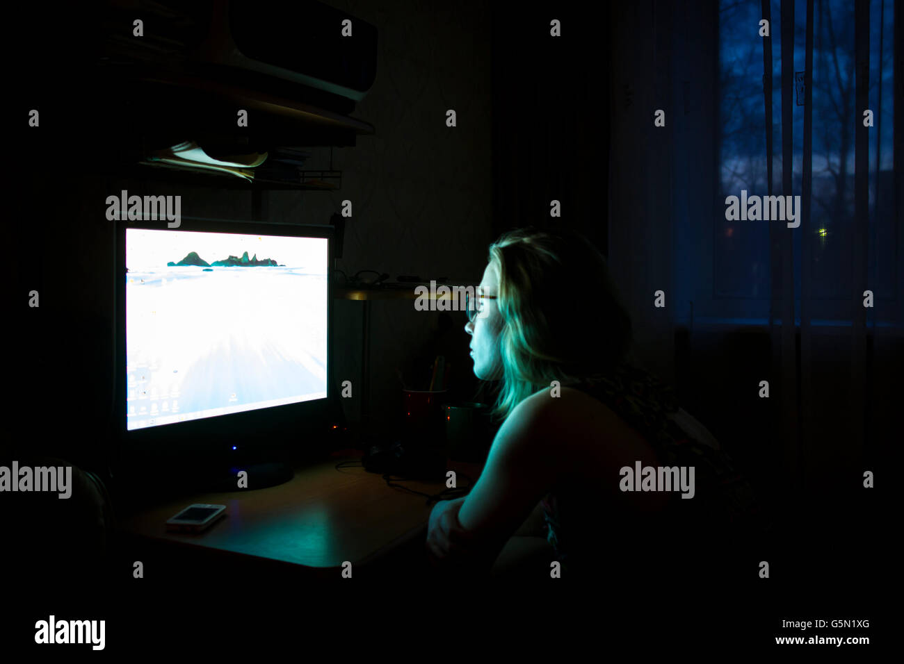 Caucasian woman using computer at night Stock Photo