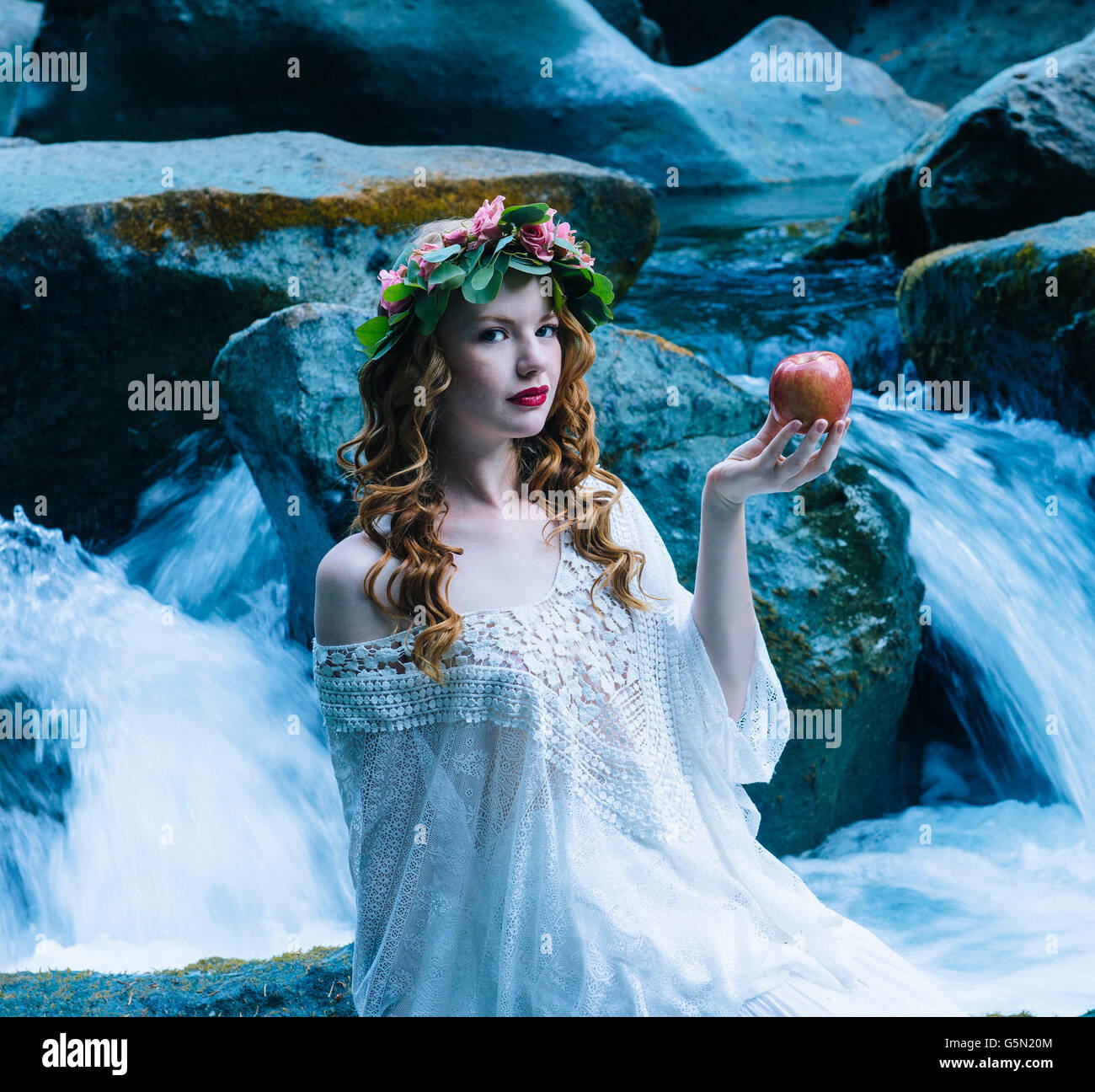 Caucasian woman holding apple at river waterfall Stock Photo