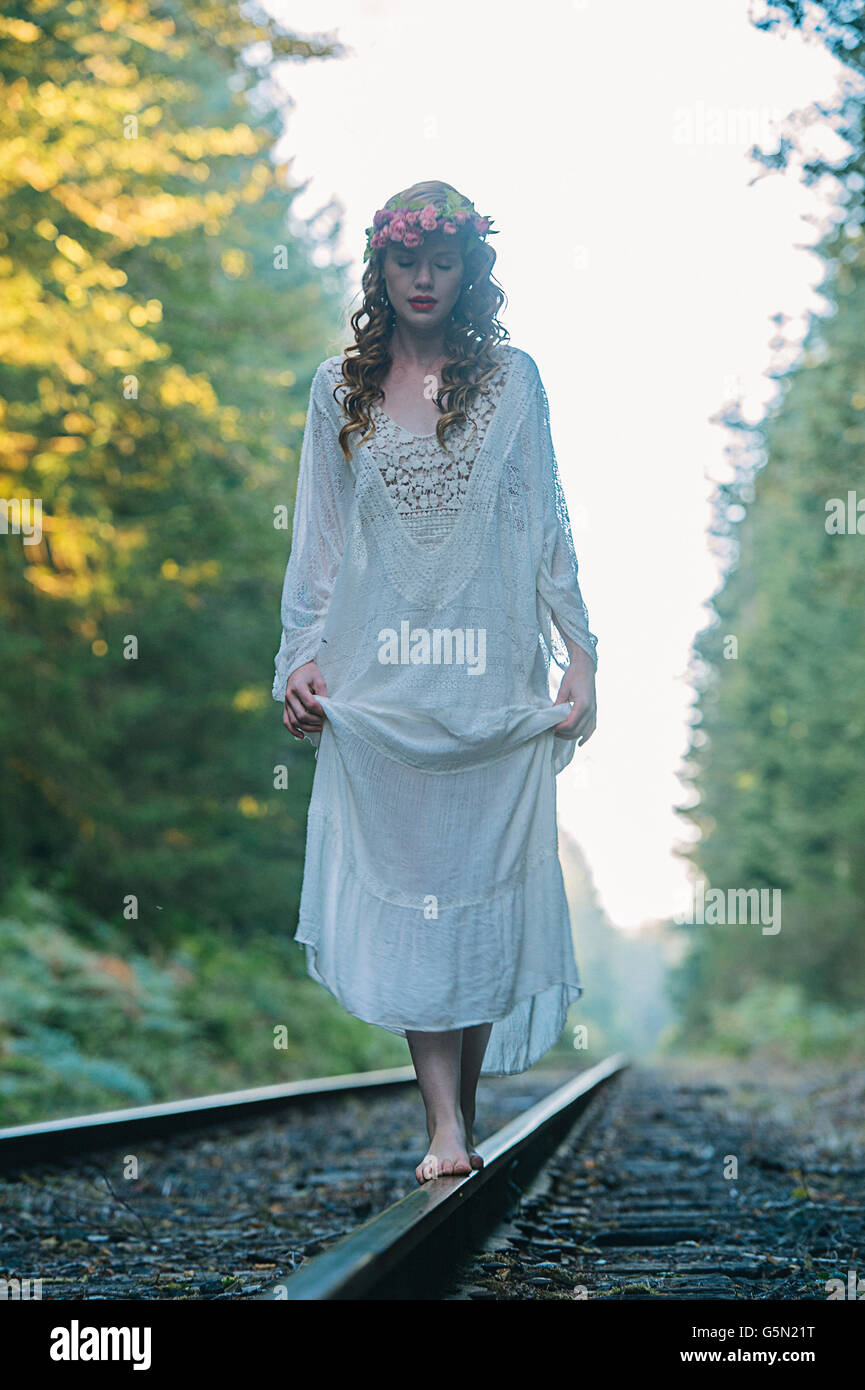 Caucasian woman balancing on train tracks in forest Stock Photo